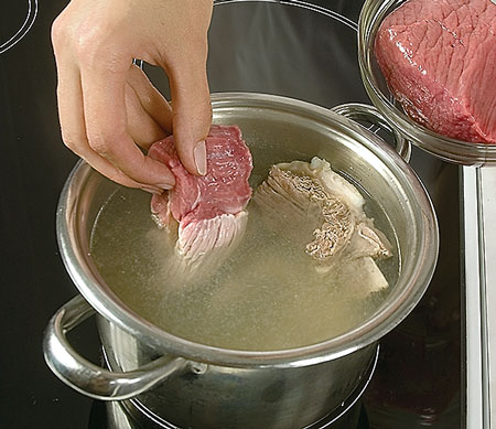Потім м'ясо вийміть, зріжте м'якоть з кісток, наріжте її порціями, бульйон процідіть