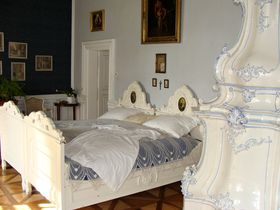 Замок Слатіняни, фото: Тереза ​​Браздова, ЧРО   Біла ліжко під пишним балдахіном, штори, вигадлива піч