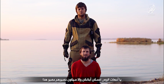 Російськомовний бойовик «Ісламської держави» стоїть на кам'янистому березі з великим ножем в руках