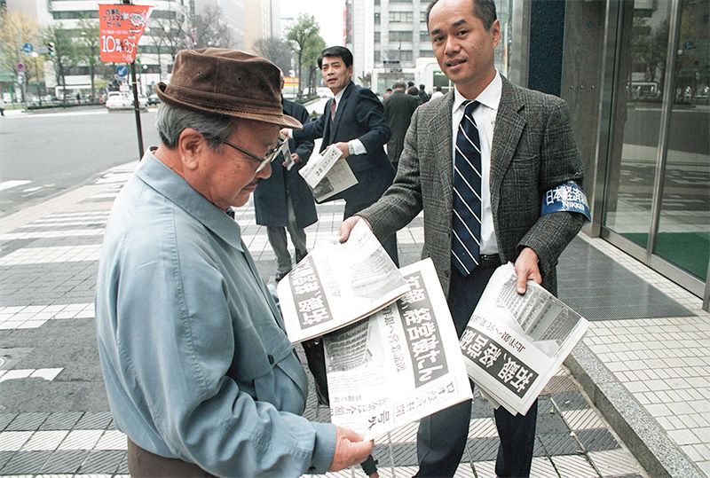 Городянин знайомиться з екстреним випуском преси під заголовком «Крах банку Такусеку» перед головним відділенням банку «Хоккайдо Такусеку», преф